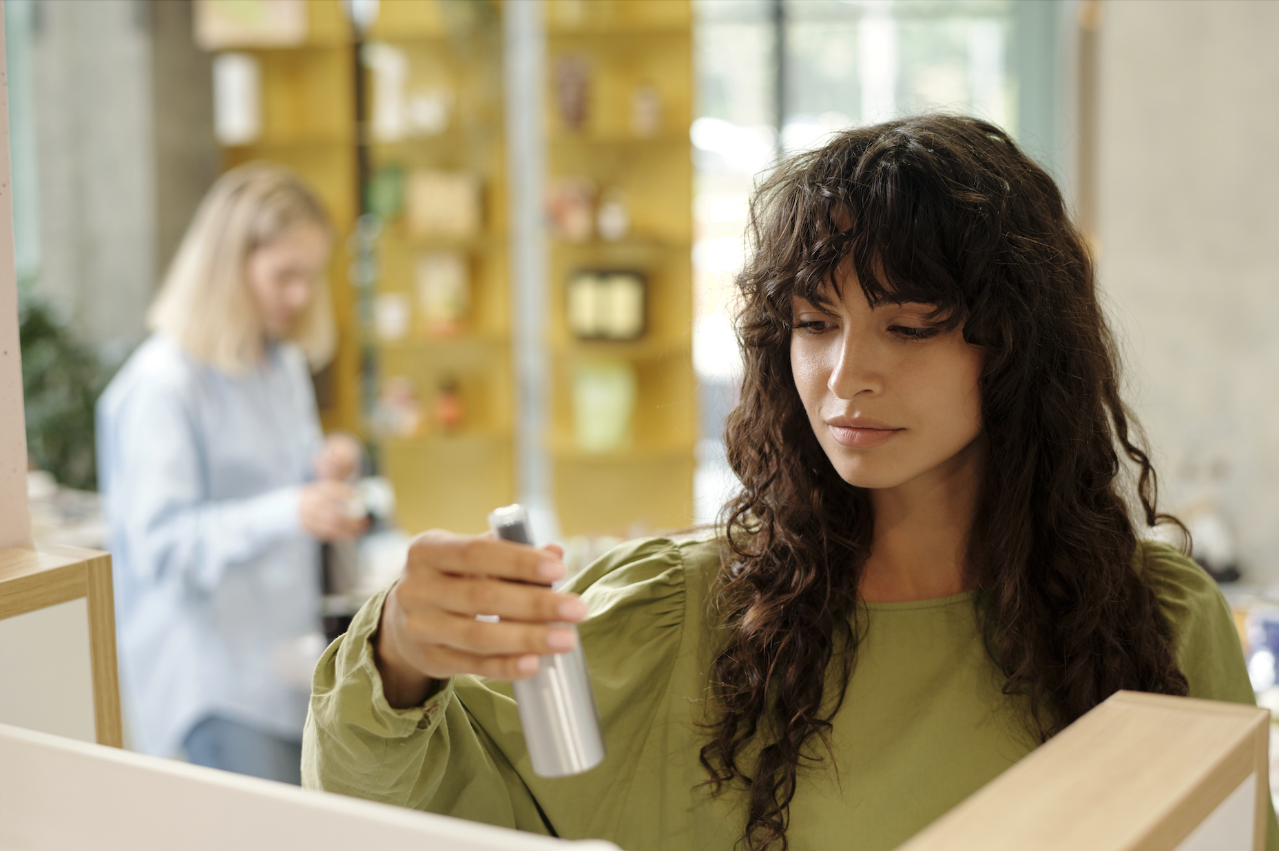 Young woman with dark long wavy hair choosing haircare product. 