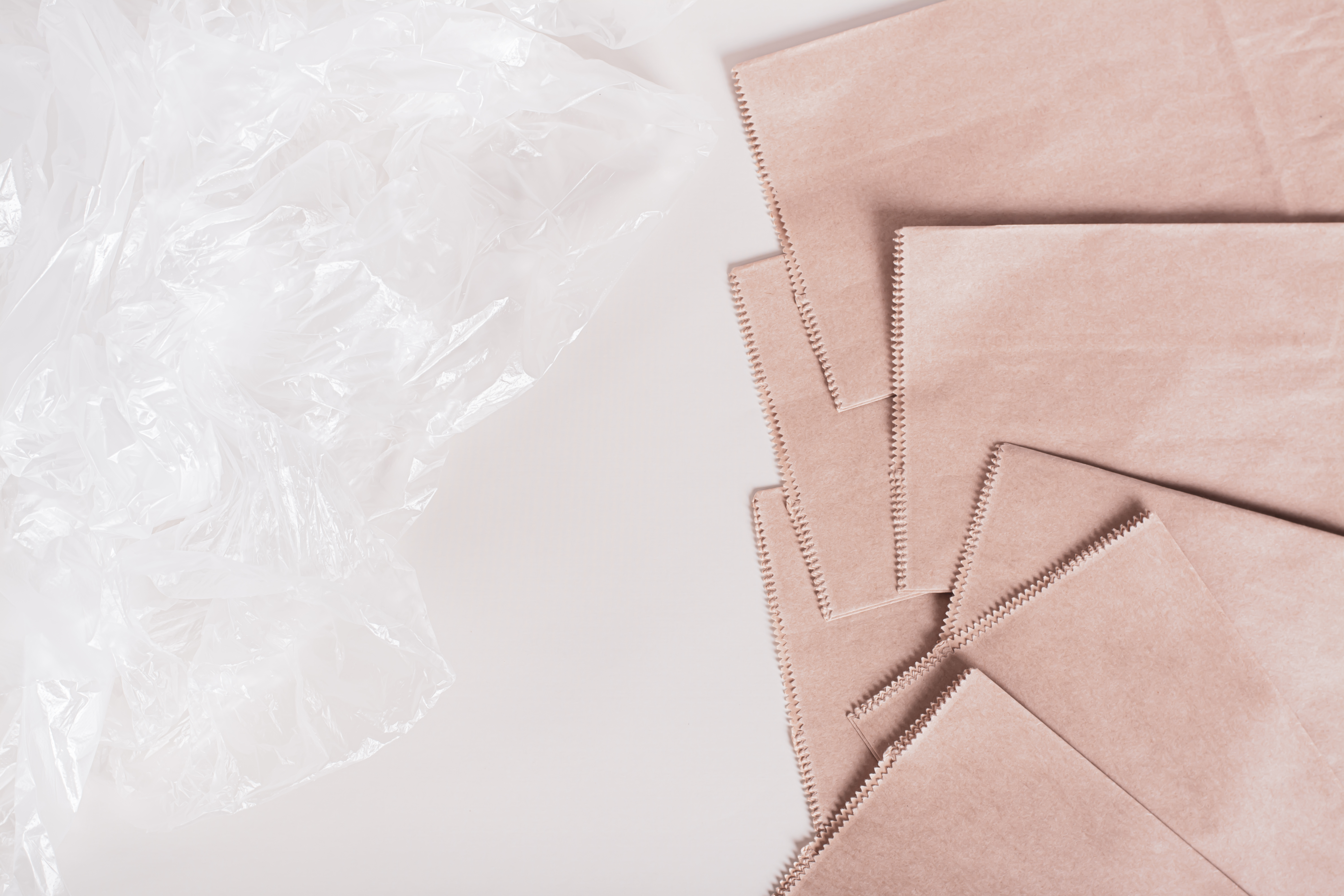 Eco-friendly paper bags and crumpled plastic bags on the table top view